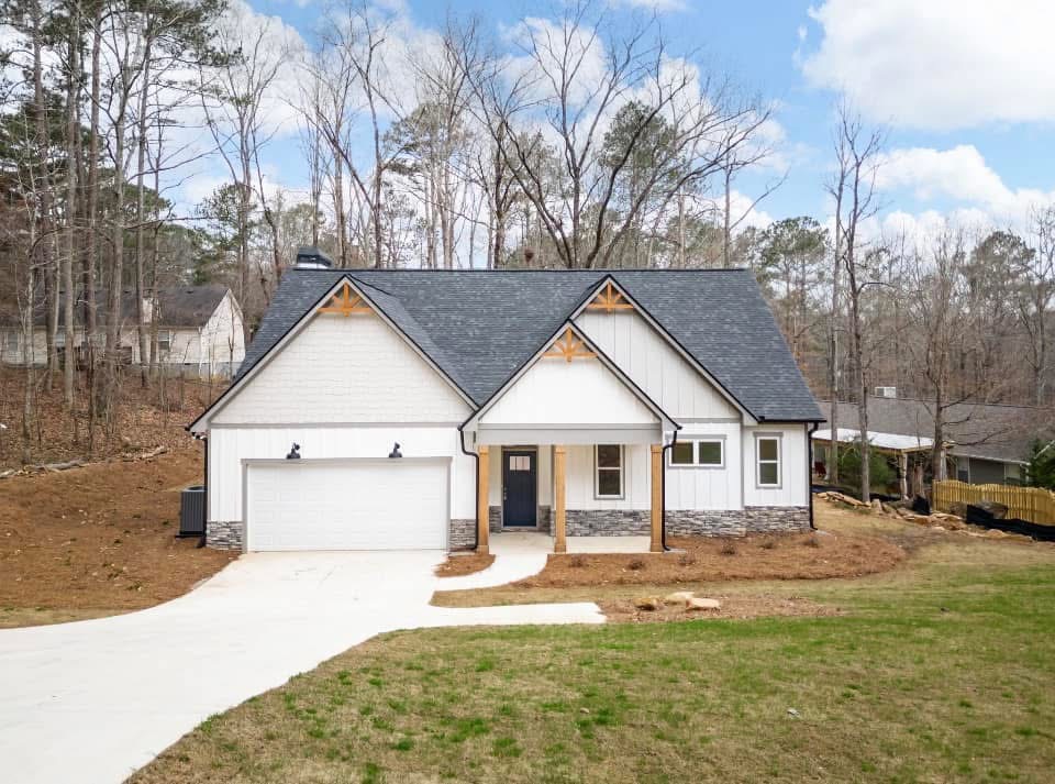 Modern custom-built home in Georgia featuring a gabled roof, two-car garage, and craftsman-style accents surrounded by wooded landscape.